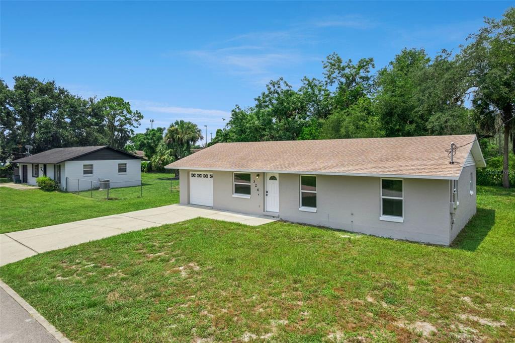 A single-story house with a light gray exterior, a tan roof, and an attached garage — 324 QUEEN AVENUE, OVIEDO, FL