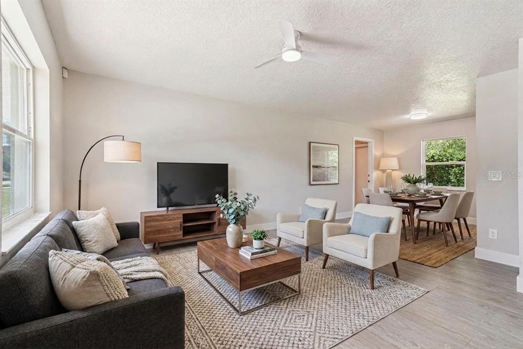A living room with a gray sofa, two armchairs, a television, and an adjacent dining area — 324 QUEEN AVENUE, OVIEDO, FL