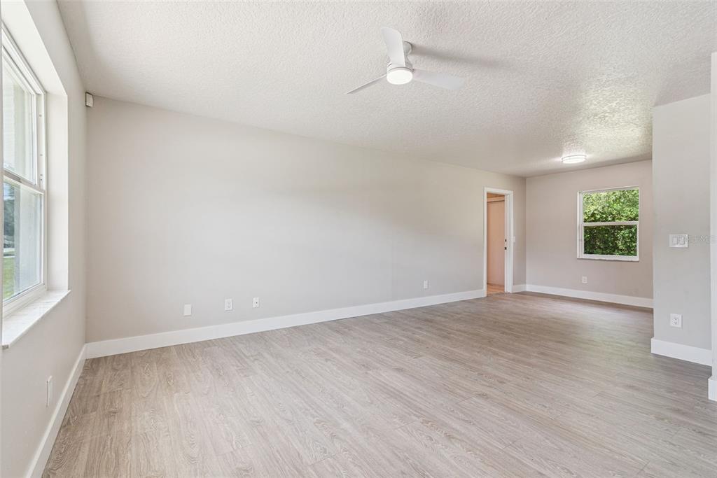 An empty room with light-colored walls, wood-look flooring, a ceiling fan, and two windows — 324 QUEEN AVENUE, OVIEDO, FL