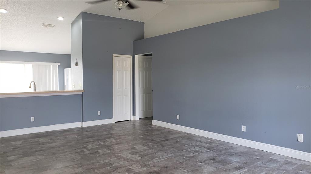 An empty room with grey walls, white trim, and grey wood-look flooring — 5141 PINE NEEDLE DRIVE, MASCOTTE, FL