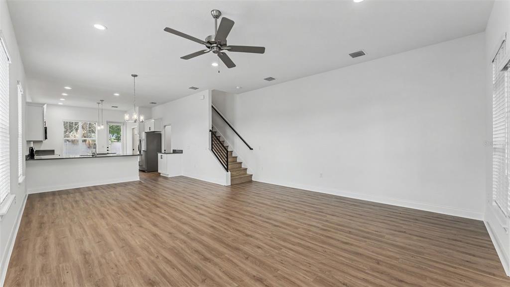 An open-concept living area features wood-look flooring, a ceiling fan, and a staircase — 1031 E LIME STREET, LAKELAND, FL