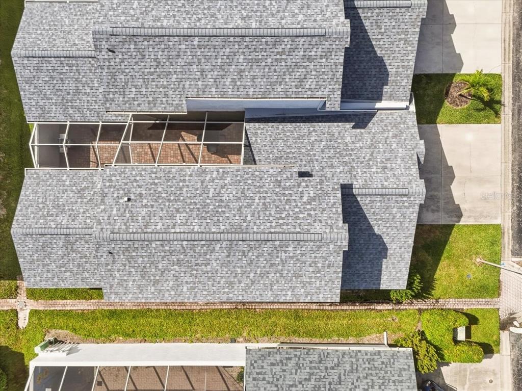 An aerial view shows the gray shingled roof of a house with a screened-in patio — 13730 DOWNING LANE UNIT W-1, FORT MYERS, FL
