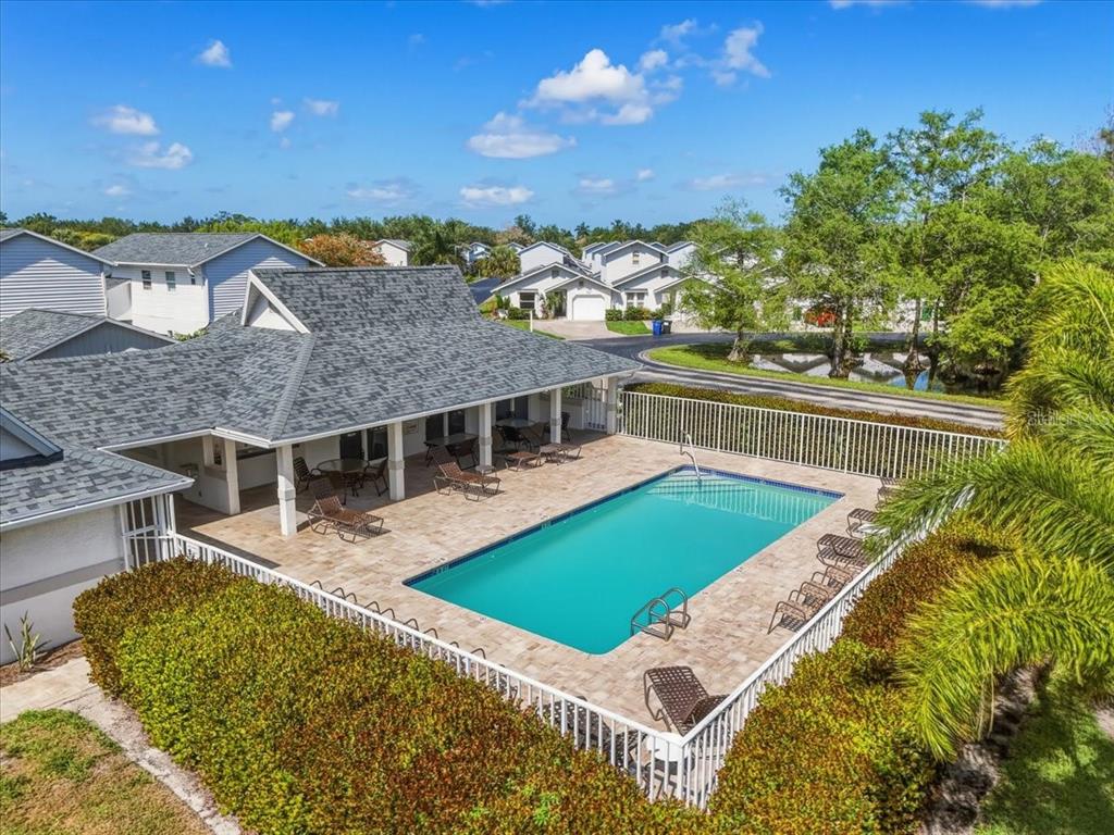An aerial view of a rectangular swimming pool with lounge chairs on a paved patio — 13730 DOWNING LANE UNIT W-1, FORT MYERS, FL