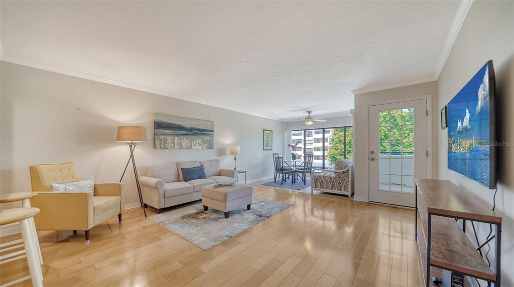 A living room with light hardwood floors, a beige sofa, a yellow armchair, and a television — 835 S OSPREY AVENUE UNIT 201, SARASOTA, FL