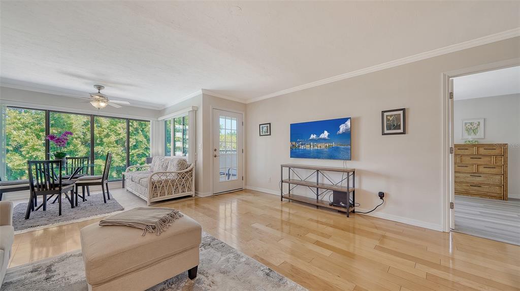 A living room with hardwood floors, a wall-mounted television, and a dining area with windows — 835 S OSPREY AVENUE UNIT 201, SARASOTA, FL