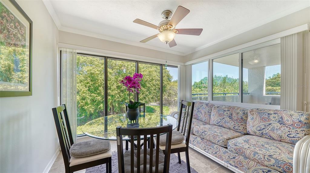 A sunroom features a glass dining table, chairs, a patterned sofa, and large windows — 835 S OSPREY AVENUE UNIT 201, SARASOTA, FL