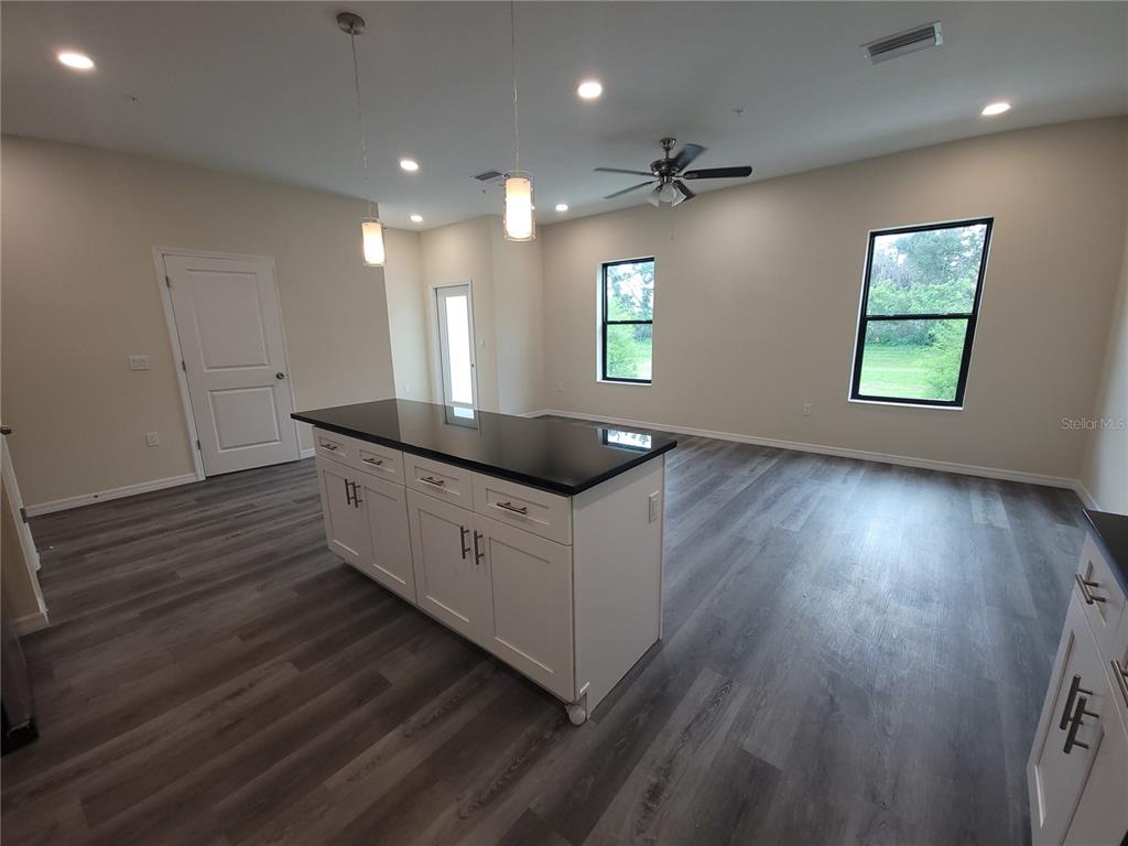 A kitchen island with a black countertop sits in a room with light-colored flooring — 4351 CAMBIO GARDENS COURT, TAMPA, FL