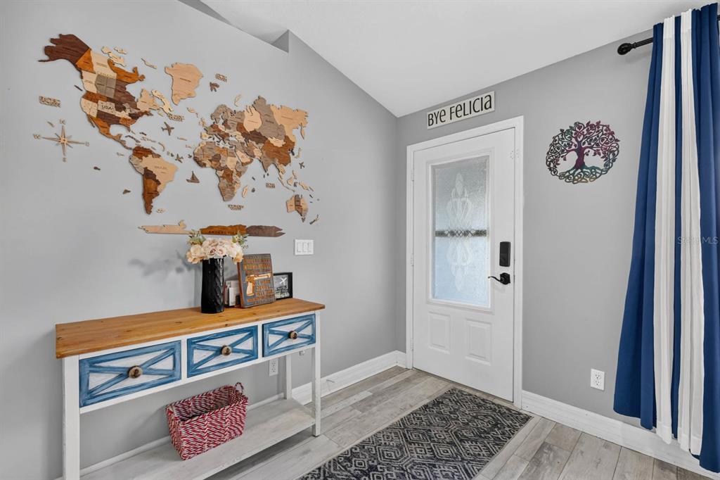 An entryway features a wooden world map wall art, a blue and white console table, and a door — 5480 SAINT REGIS WAY, PORT ORANGE, FL