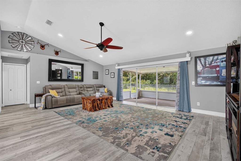 A living room with gray walls, wood-look flooring, a large area rug, and sliding glass doors — 5480 SAINT REGIS WAY, PORT ORANGE, FL