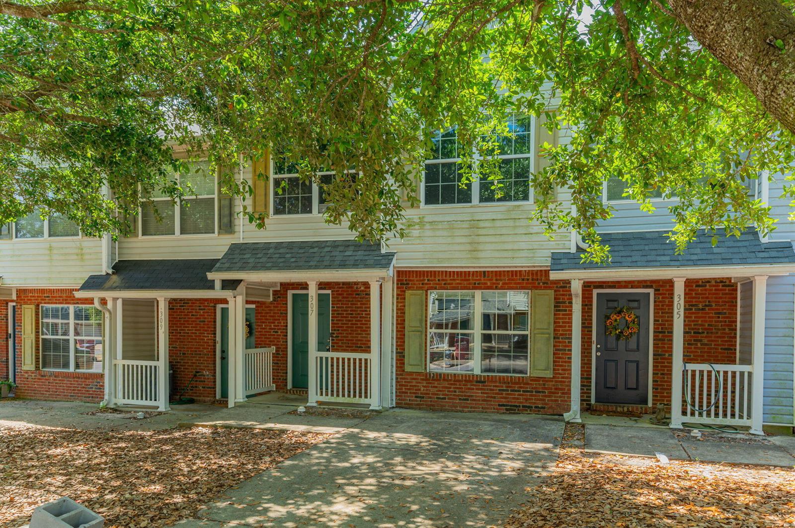 A row of two-story townhomes with brick facades, white railings, and front entry doors — 307 Crooked Pine Trail, FL 32539, FL