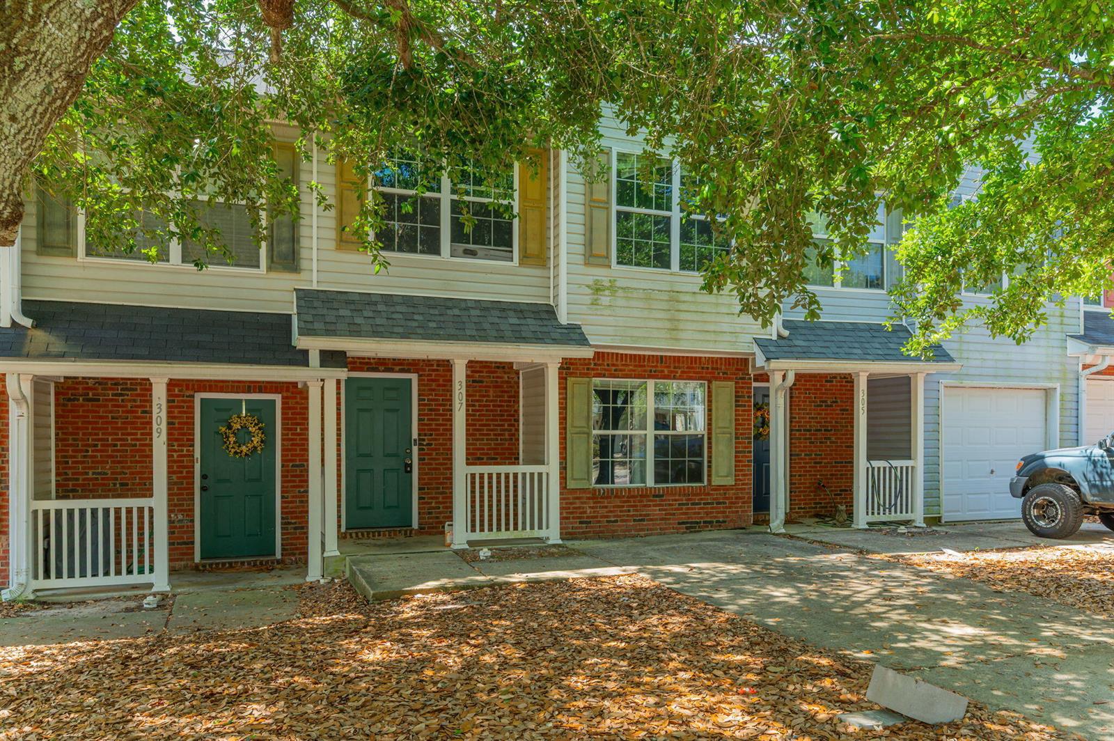 A row of three-story townhomes with brick facades, covered porches, and a concrete driveway — 307 Crooked Pine Trail, FL 32539, FL