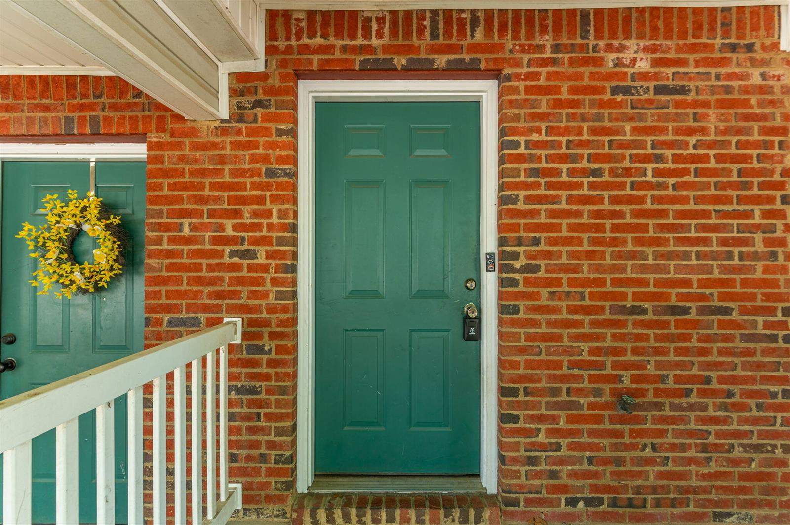 A green front door with a smart lock is set into a red brick wall — 307 Crooked Pine Trail, FL 32539, FL