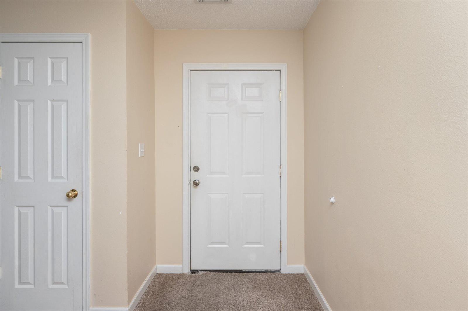 An entryway features beige walls, carpeted flooring, a white interior door, and a white front door — 307 Crooked Pine Trail, FL 32539, FL