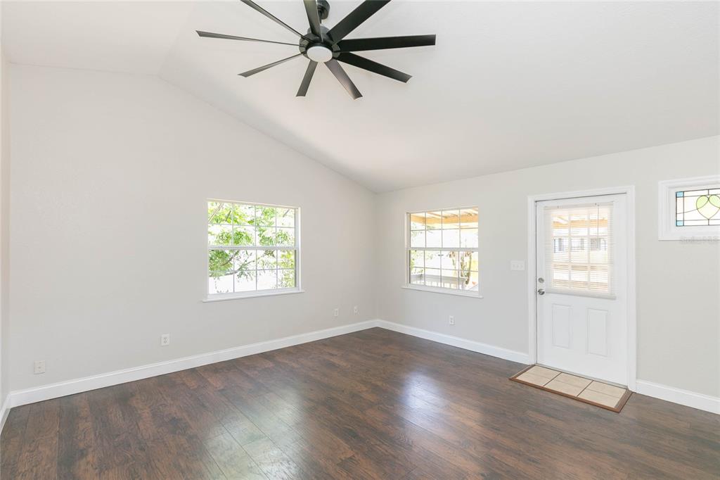 A room with dark wood flooring, light walls, a vaulted ceiling, and a ceiling fan — 13410 LEE STREET, DADE CITY, FL