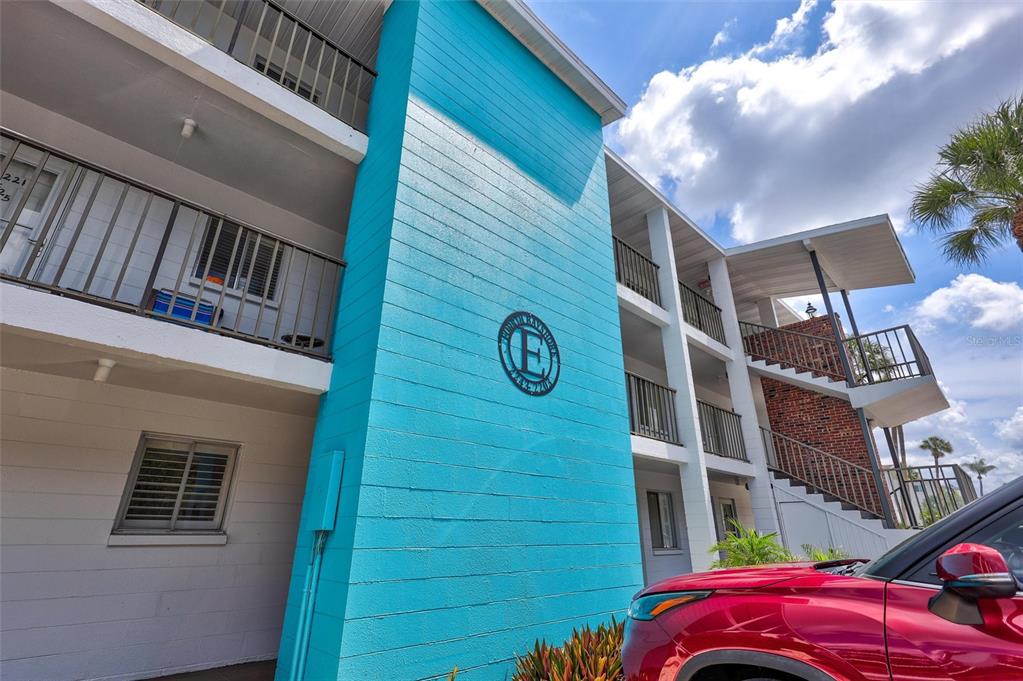 A bright blue exterior wall with a circular sign marks this multi-story apartment building — 2217 SUNSET DRIVE UNIT E27, BRADENTON, FL