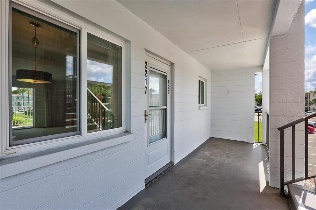 A white exterior wall features a front door and a window on a concrete walkway — 2217 SUNSET DRIVE UNIT E27, BRADENTON, FL