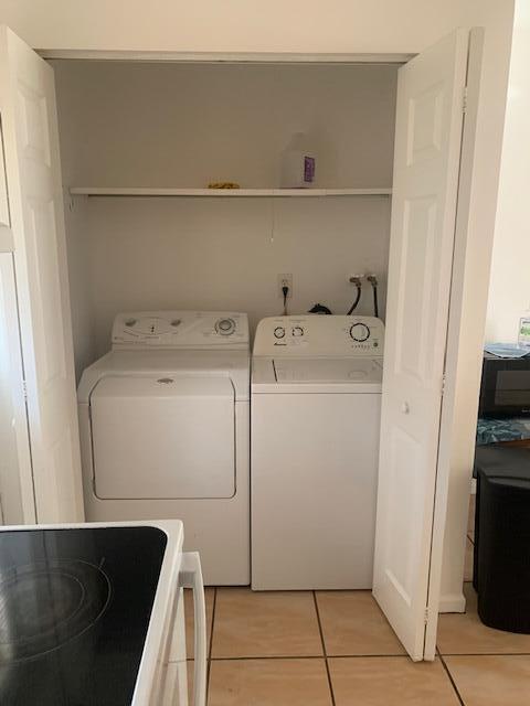 A laundry closet contains a white washer and dryer beneath a single storage shelf — 933 Francis Street, West Palm Beach FL 33405, WEST PALM BEACH, FL