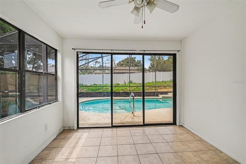 A sunroom with tile flooring, a ceiling fan, and sliding glass doors overlooking a pool — 7774 BARBERRY DRIVE, ORLANDO, FL
