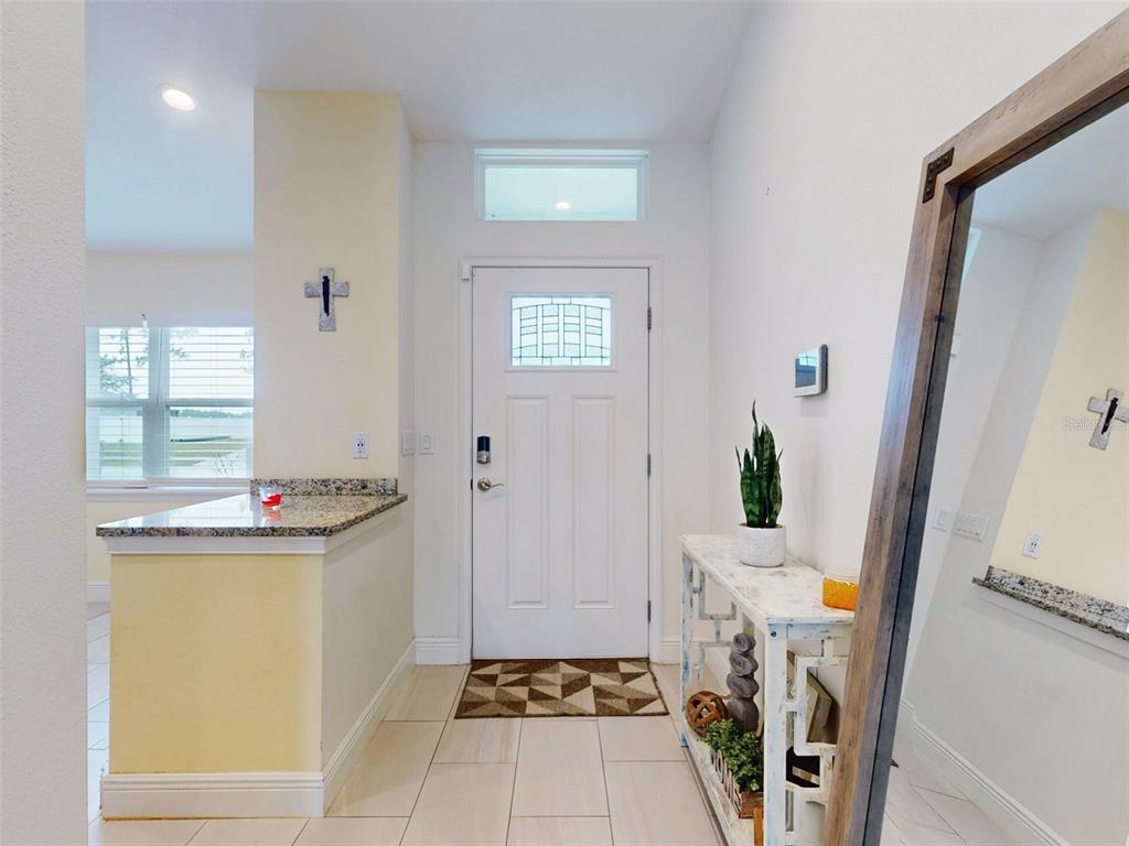 An entryway features a white front door, tile flooring, a console table, and a mirror — 2684 SHIPROCK COURT, DELTONA, FL