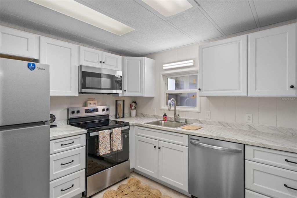 A kitchen with white cabinets, stainless steel appliances, and marble-look countertops — 3450 OSAGE DRIVE, ZEPHYRHILLS, FL