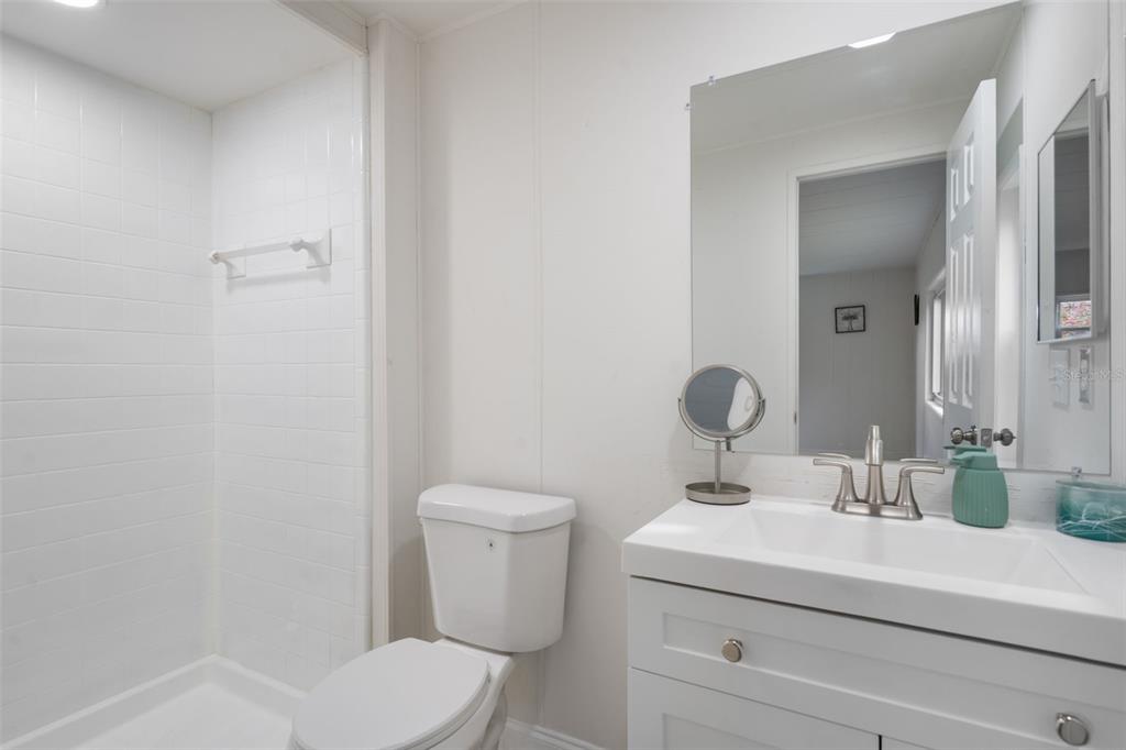 A bathroom features a white vanity, a toilet, and a tiled walk-in shower — 3450 OSAGE DRIVE, ZEPHYRHILLS, FL