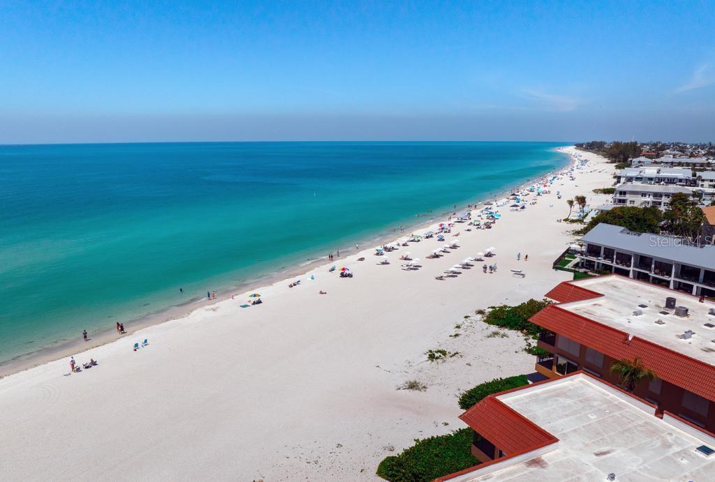 An aerial view of a white sand beach along a turquoise ocean with nearby buildings — 6005 GULF DRIVE UNIT 219, HOLMES BEACH, FL
