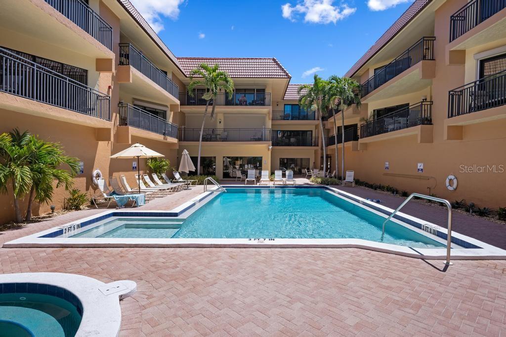 A swimming pool with a surrounding patio and lounge chairs sits between two apartment buildings — 6005 GULF DRIVE UNIT 219, HOLMES BEACH, FL
