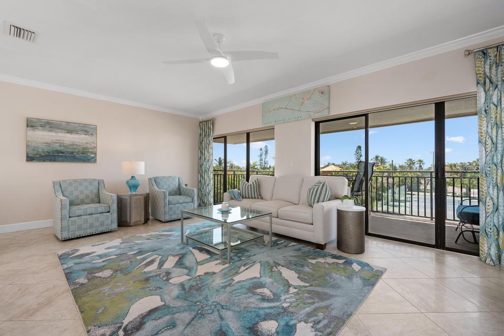 A living room with a white sofa, two patterned armchairs, and a large area rug — 6005 GULF DRIVE UNIT 219, HOLMES BEACH, FL