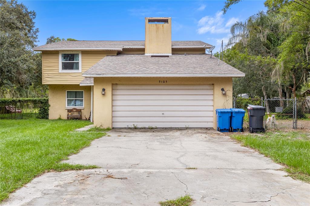 A two-story house with yellow siding, a concrete driveway, and a large central chimney — 5105 FIVE ACRE ROAD, PLANT CITY, FL
