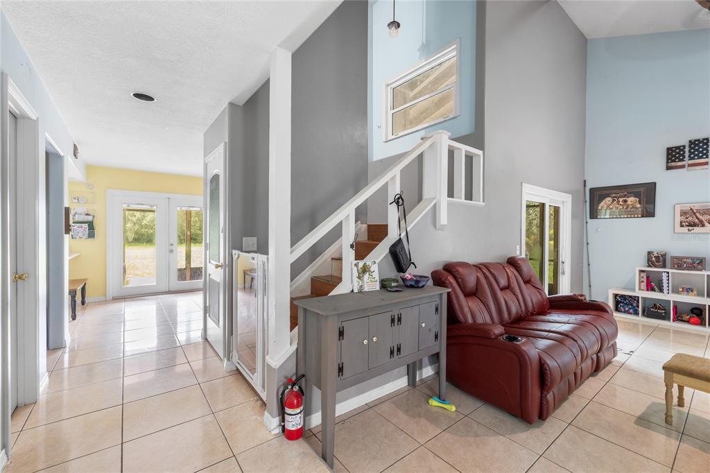 A living room with tile floors, a red leather sofa, and a staircase with white railings — 5105 FIVE ACRE ROAD, PLANT CITY, FL