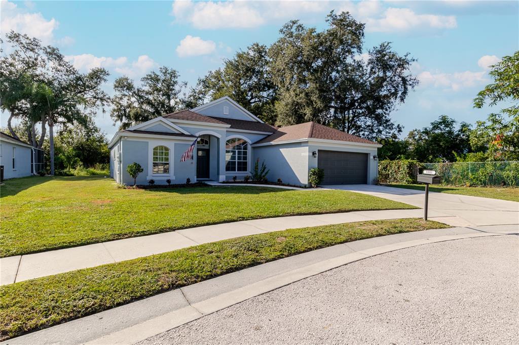 A single-story house with a gray exterior, a two-car garage, and a front lawn — 1001 ENGLISH BLUFFS COURT, BRANDON, FL