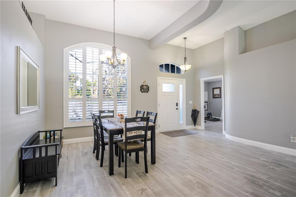 A dining area with wood-look tile floors, a chandelier, and a large arched window — 1001 ENGLISH BLUFFS COURT, BRANDON, FL