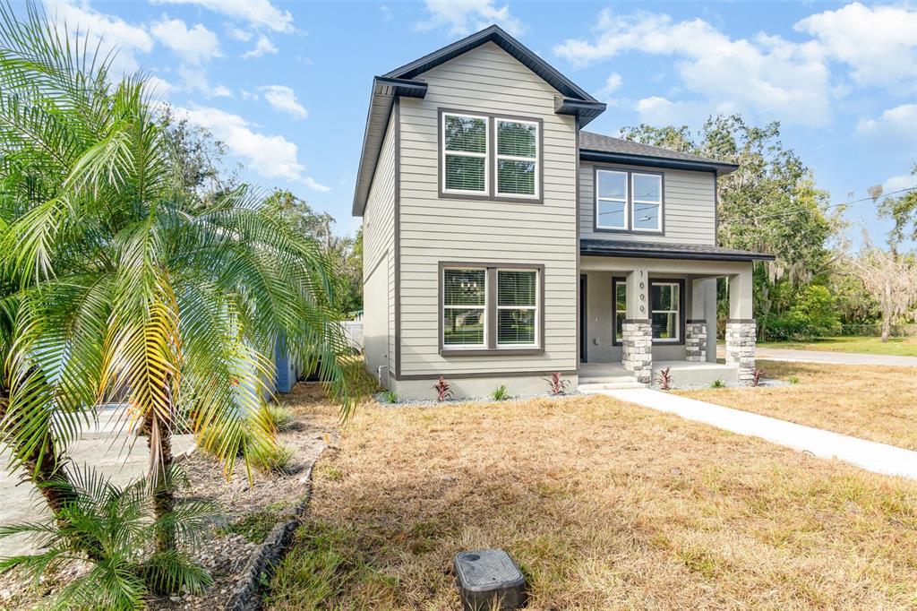A two-story house with light-colored siding, a front porch, and a palm tree in front — 1000 S LOCUST AVENUE, SANFORD, FL
