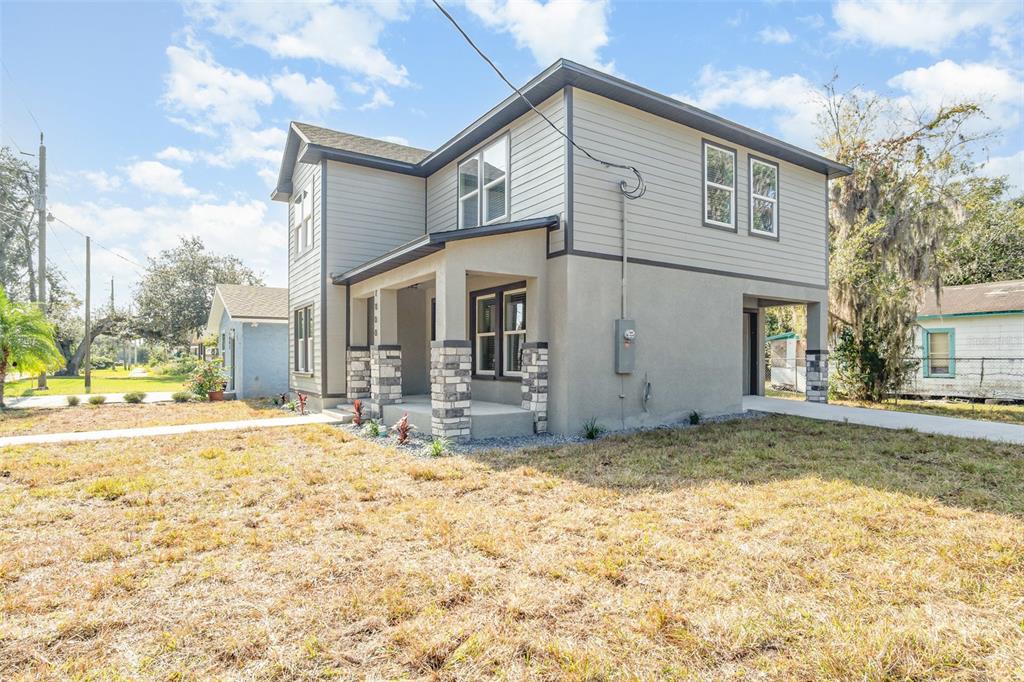 A two-story house with gray siding, stucco, and stone accents features a front porch — 1000 S LOCUST AVENUE, SANFORD, FL