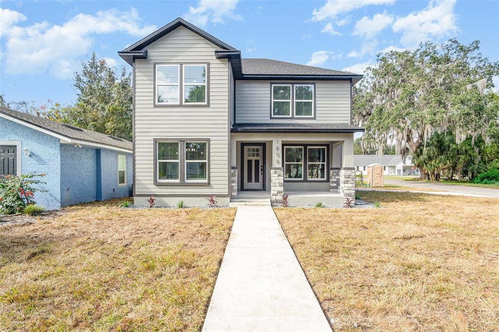 A two-story house with gray horizontal siding, stone accents, and a concrete walkway — 1000 S LOCUST AVENUE, SANFORD, FL