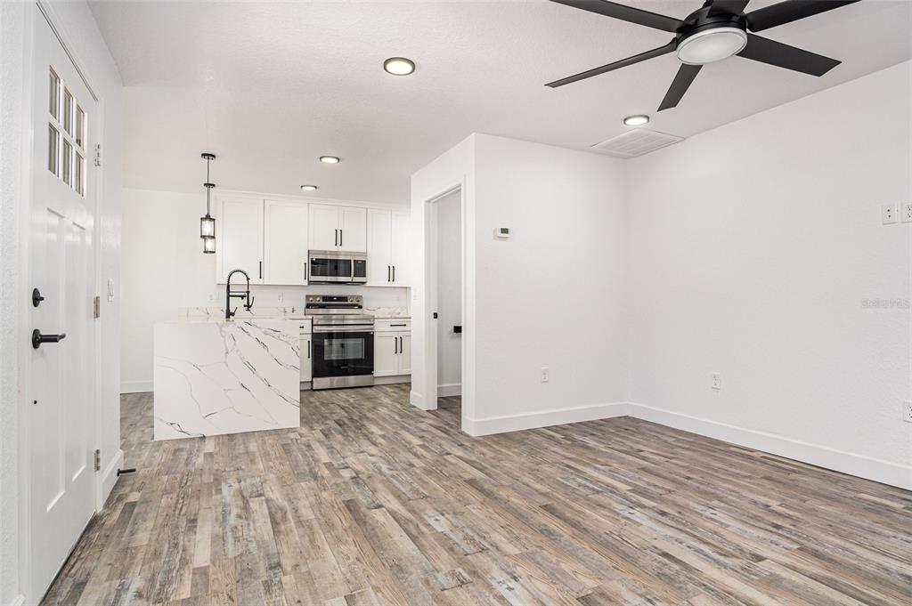 A kitchen with white cabinets and a marble-patterned island opens into a living area — 1000 S LOCUST AVENUE, SANFORD, FL