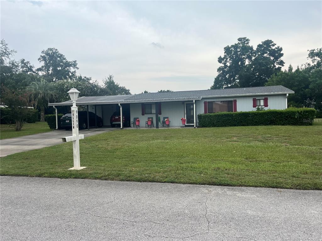 A single-story house with a metal roof, attached carport, and a large front lawn — 9090 SW 104TH PLACE, OCALA, FL