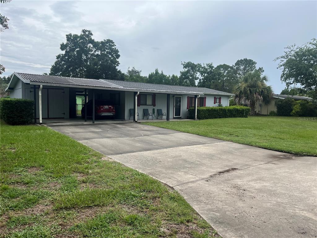 A single-story house with a carport, concrete driveway, and a large tree in the yard — 9090 SW 104TH PLACE, OCALA, FL