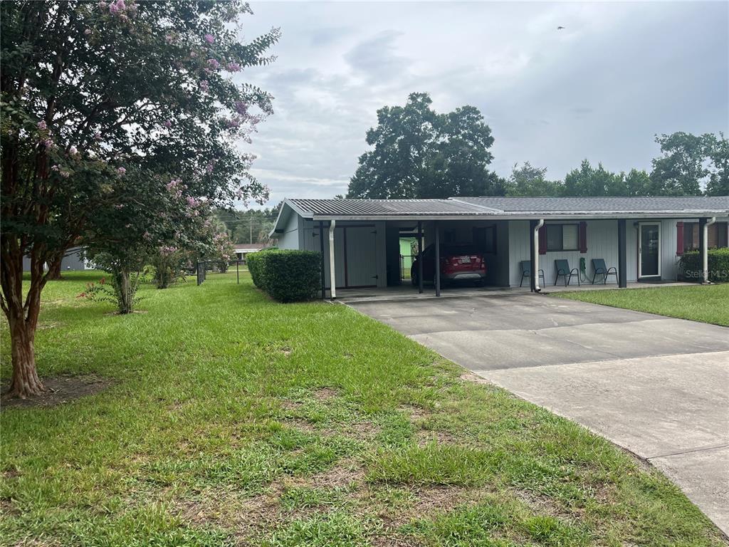 A fenced backyard features a grassy lawn, a concrete patio, and a light-colored house exterior — 9090 SW 104TH PLACE, OCALA, FL