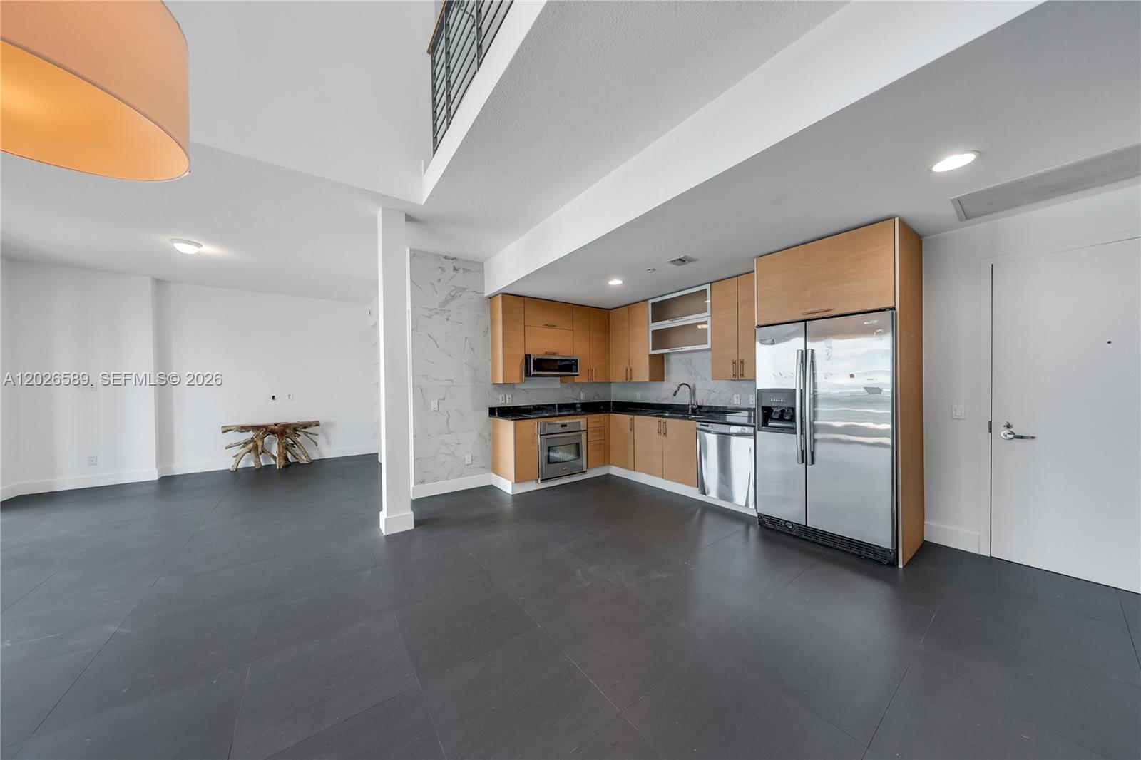A modern kitchen features light wood cabinets, stainless steel appliances, and dark tile flooring — 60 SW 13th St # 4404, Miami FL 33130, MIAMI, FL