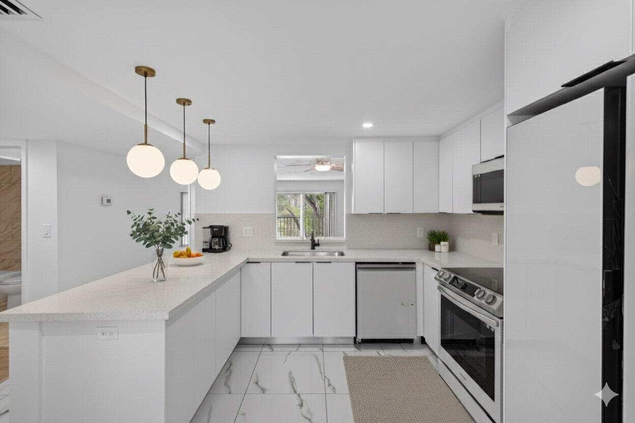 A modern white kitchen features marble-look tile floors, stainless steel appliances, and a breakfast bar — 14375 Strathmore Lane # 303, Delray Beach FL 33446, DELRAY BEACH, FL