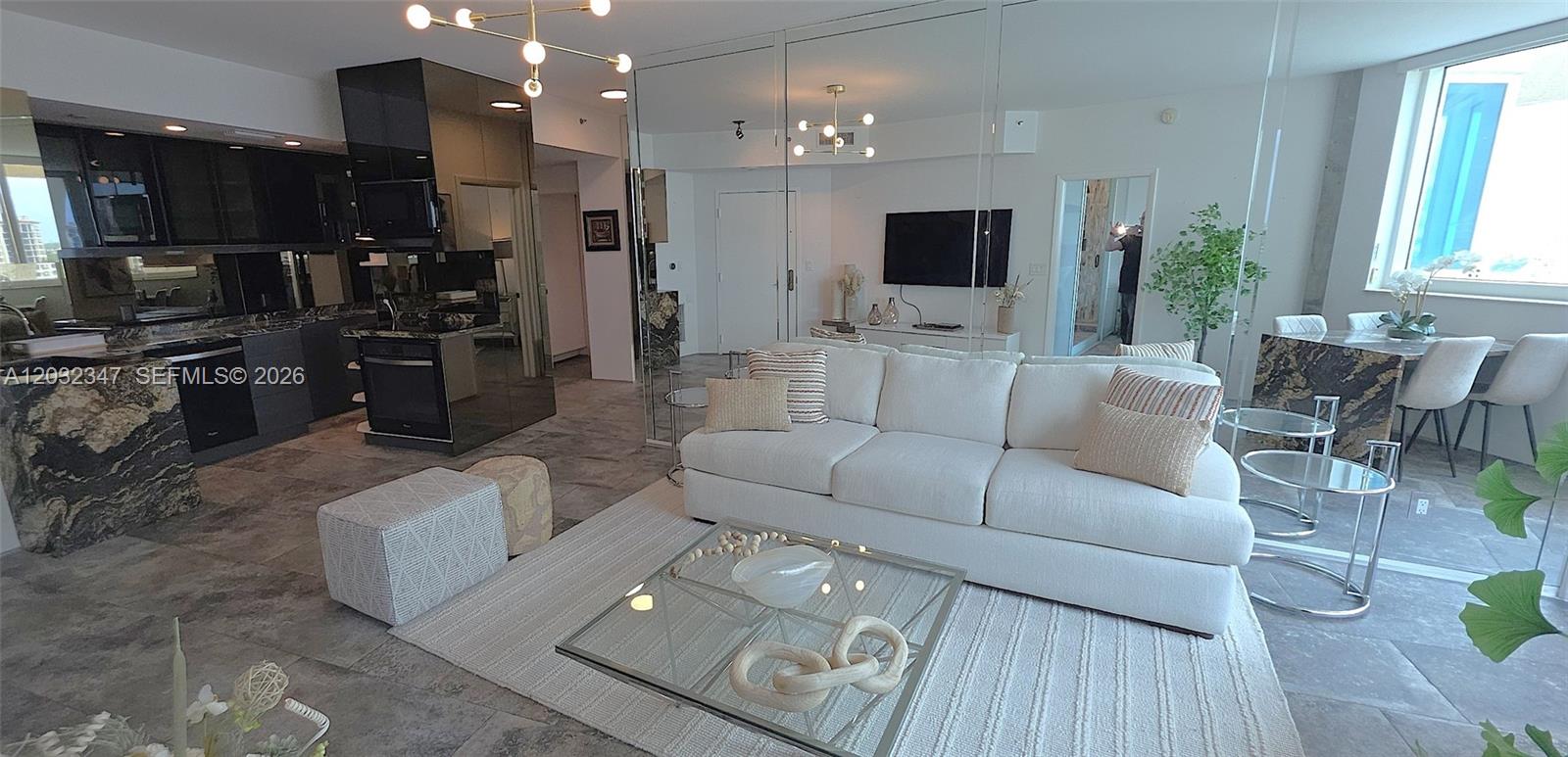 A modern living room features a white sofa, glass coffee table, and dark marble kitchen — 300 S Pointe Dr # 908, Miami Beach FL 33139, MIAMI BEACH, FL