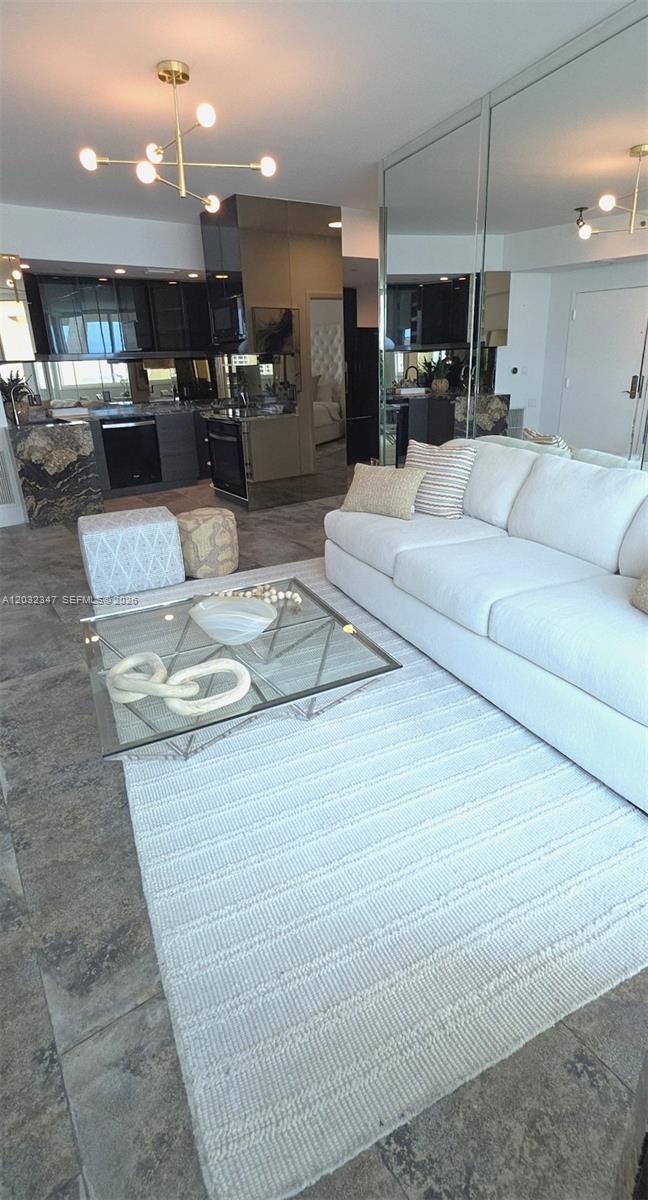 A modern living room features a white sofa, glass coffee table, and an open kitchen — 300 S Pointe Dr # 908, Miami Beach FL 33139, MIAMI BEACH, FL