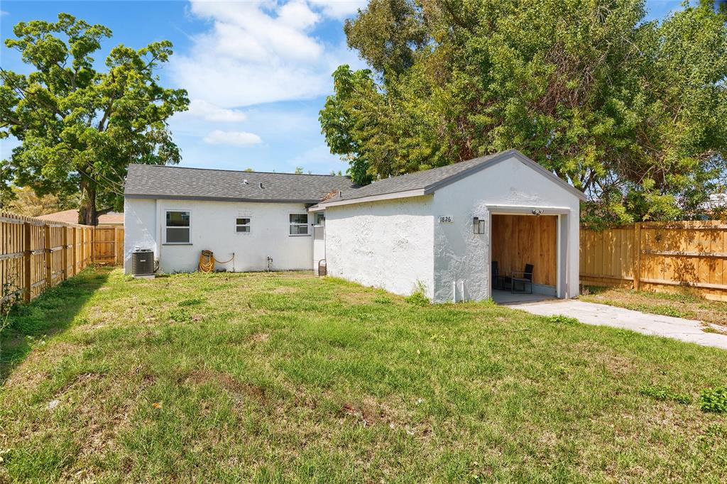 A white stucco house features a detached garage and a fenced backyard with green grass — 1826 30TH STREET S, ST PETERSBURG, FL