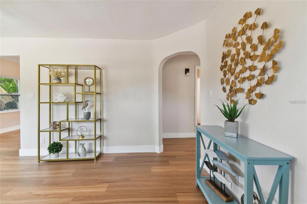 A room with wood-look flooring, a gold metal shelving unit, and a blue console table — 1826 30TH STREET S, ST PETERSBURG, FL