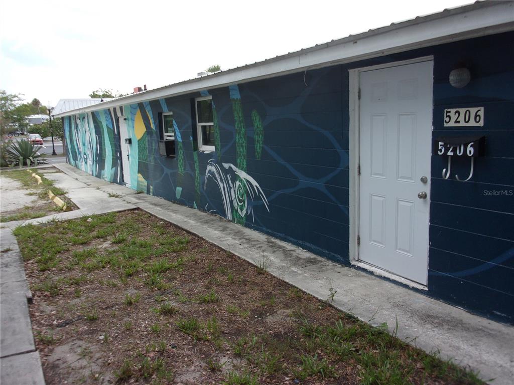 An exterior view of a blue building with a mural and a white door — 5206 7TH STREET, ZEPHYRHILLS, FL