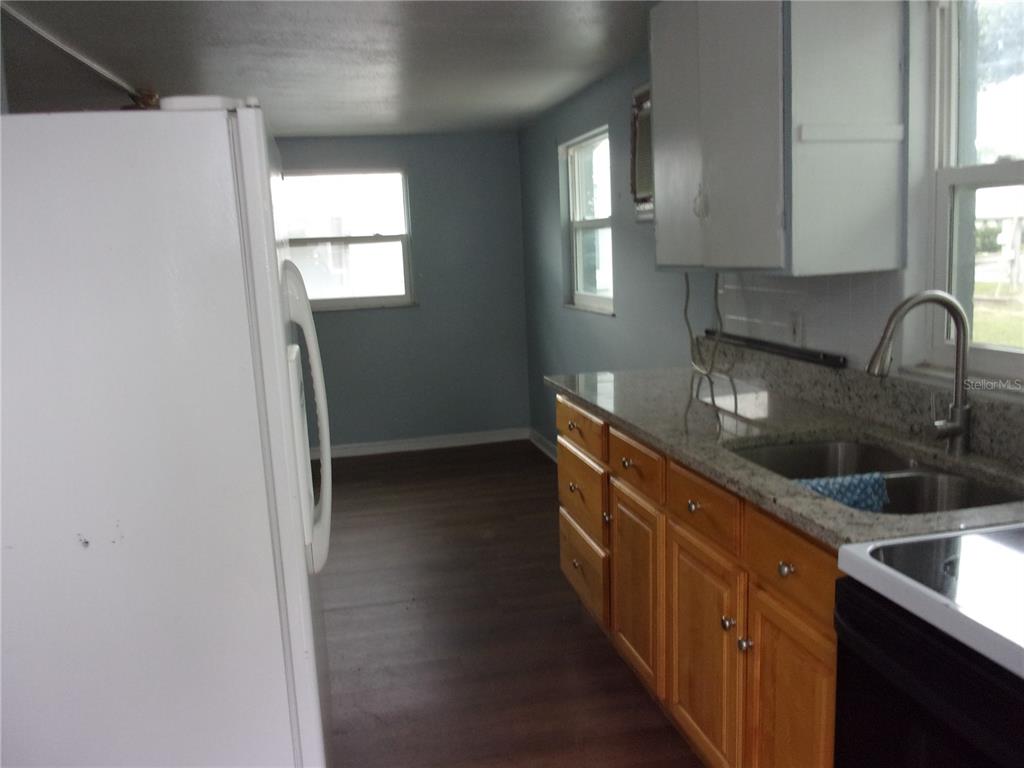 A kitchen features wood cabinets, granite countertops, a double sink, and a white refrigerator — 5206 7TH STREET, ZEPHYRHILLS, FL