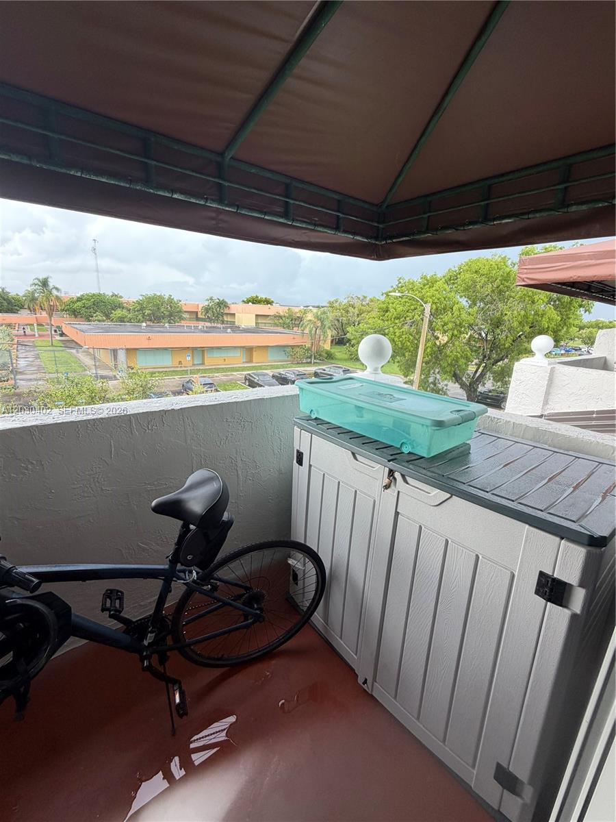 A balcony features a bicycle, a storage cabinet, and a turquoise bin under an awning — 675 NW 85th Ct # 207, Miami FL 33126, MIAMI, FL