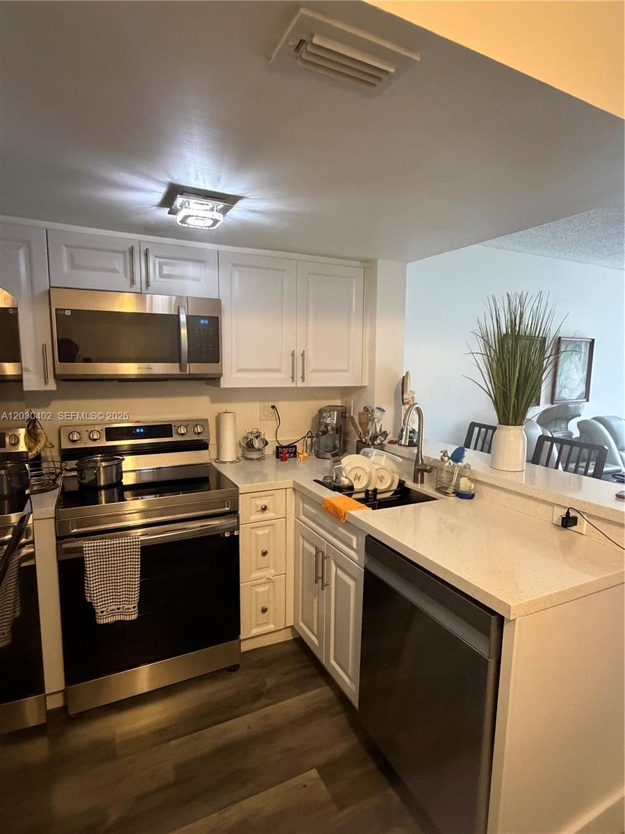 A kitchen features white cabinets, stainless steel appliances, and light-colored countertops — 675 NW 85th Ct # 207, Miami FL 33126, MIAMI, FL