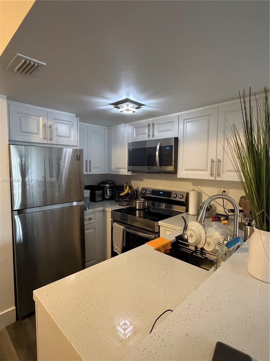 A kitchen features white cabinetry, stainless steel appliances, and a light-colored quartz countertop — 675 NW 85th Ct # 207, Miami FL 33126, MIAMI, FL